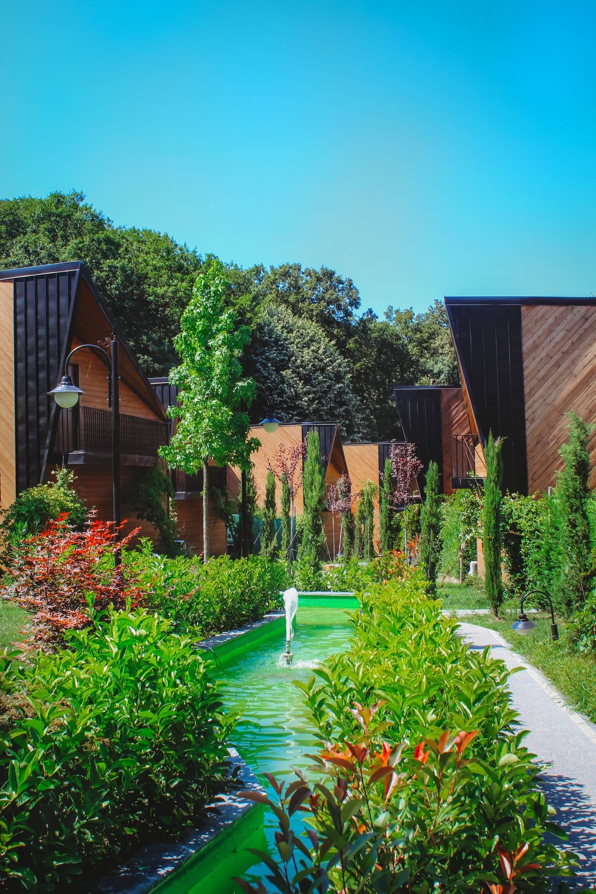 A fountain and water channel between planted garden beds